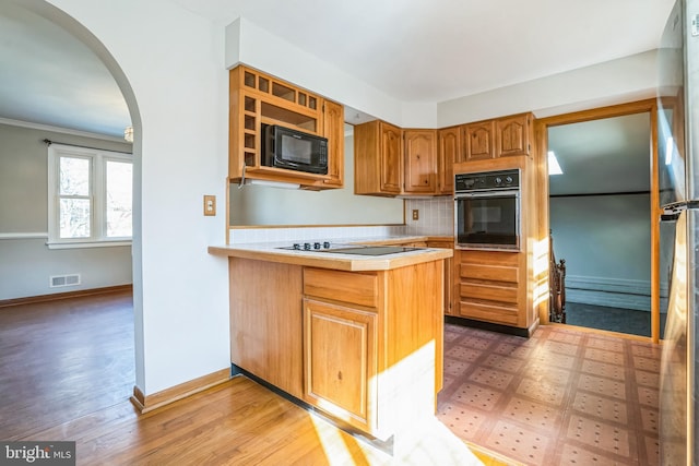 kitchen featuring wood-type flooring, kitchen peninsula, decorative backsplash, and black appliances