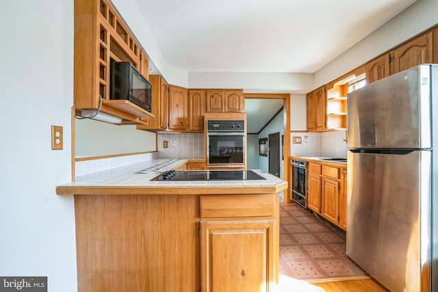 kitchen featuring backsplash, tile counters, black appliances, beverage cooler, and kitchen peninsula