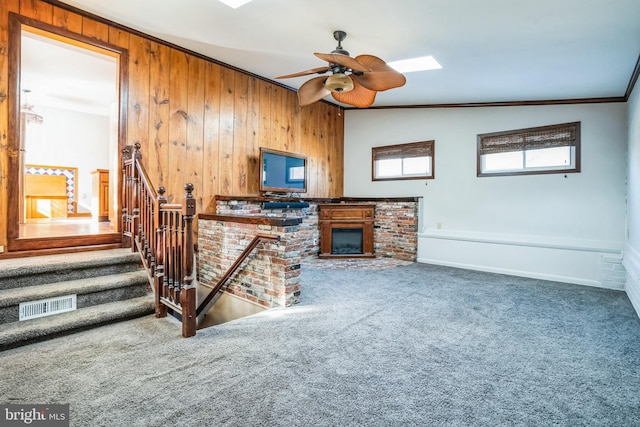 carpeted living room featuring ornamental molding, lofted ceiling, ceiling fan, and wood walls