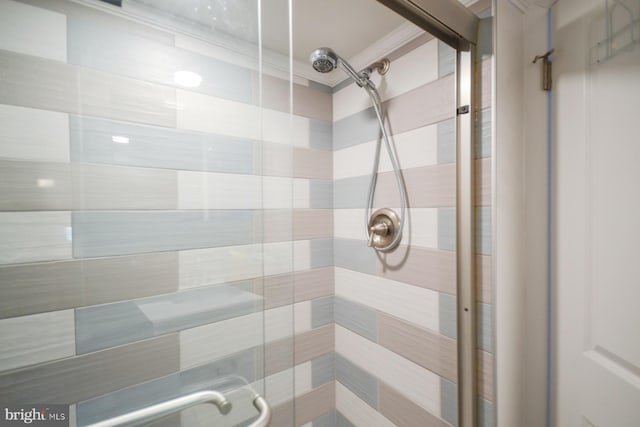 bathroom with a shower with door and ornamental molding