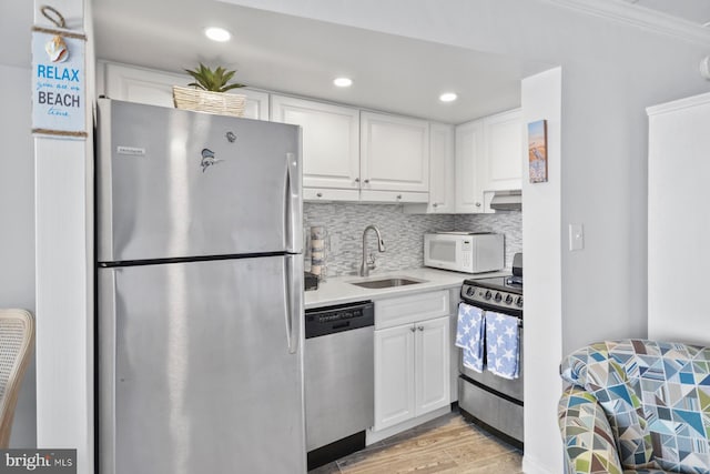 kitchen with white cabinetry, sink, stainless steel appliances, crown molding, and light wood-type flooring