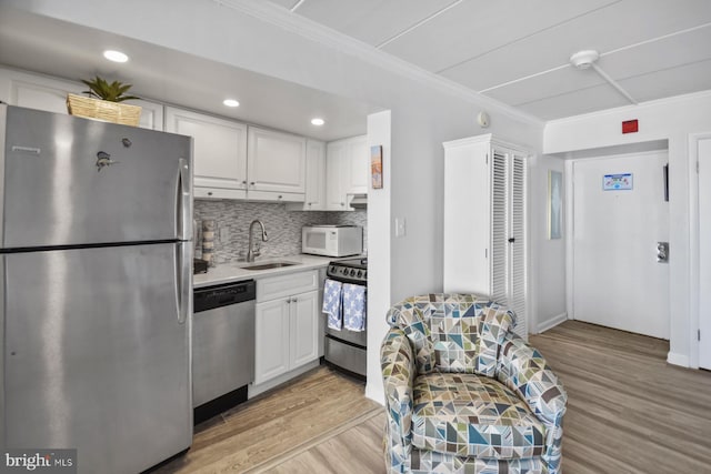 kitchen featuring sink, appliances with stainless steel finishes, light hardwood / wood-style floors, white cabinets, and ornamental molding