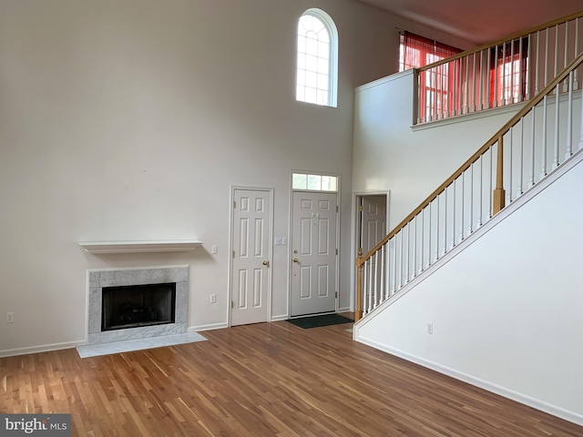 unfurnished living room with hardwood / wood-style floors, a healthy amount of sunlight, and a high ceiling