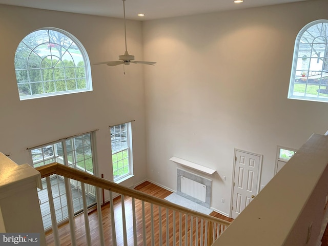 stairs with hardwood / wood-style flooring, ceiling fan, and high vaulted ceiling