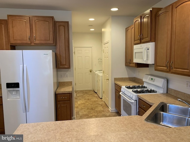 kitchen featuring white appliances, washer and clothes dryer, and sink