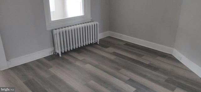 unfurnished room featuring radiator and dark wood-type flooring