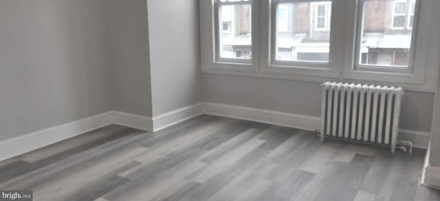 unfurnished room featuring radiator heating unit and wood-type flooring