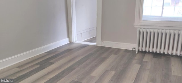 unfurnished bedroom featuring radiator heating unit and dark hardwood / wood-style flooring