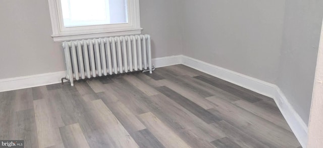 empty room featuring dark hardwood / wood-style flooring and radiator heating unit