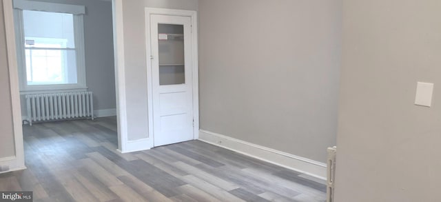 unfurnished room featuring hardwood / wood-style floors and radiator heating unit