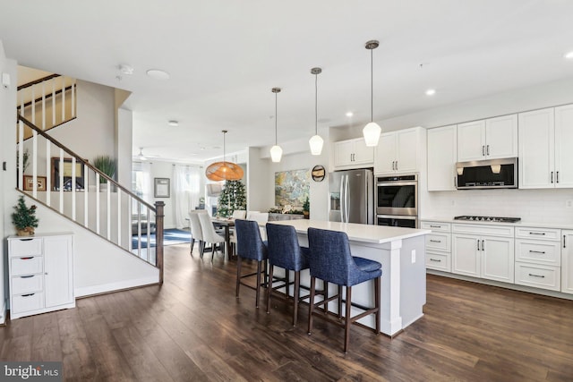 kitchen featuring white cabinetry, a center island, dark wood-type flooring, and appliances with stainless steel finishes