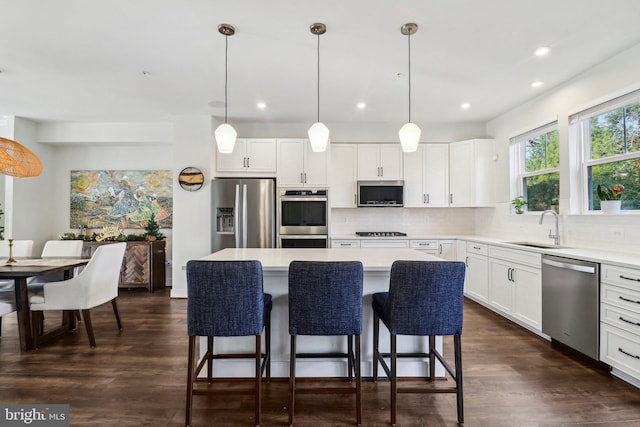 kitchen featuring pendant lighting, a center island, white cabinets, and stainless steel appliances