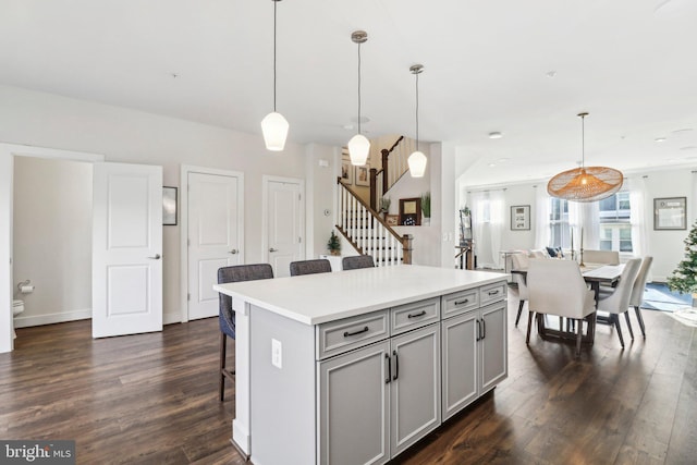 kitchen featuring decorative light fixtures, a kitchen island, and dark wood-type flooring