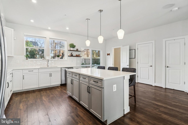 kitchen with pendant lighting, dishwasher, a center island, dark hardwood / wood-style floors, and a breakfast bar area