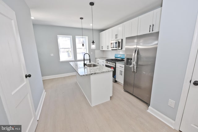 kitchen featuring white cabinets, sink, stainless steel appliances, and an island with sink