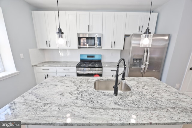 kitchen with pendant lighting, sink, an island with sink, appliances with stainless steel finishes, and white cabinetry