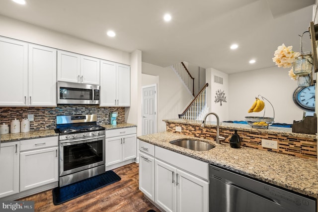 kitchen with sink, appliances with stainless steel finishes, tasteful backsplash, dark hardwood / wood-style flooring, and white cabinetry