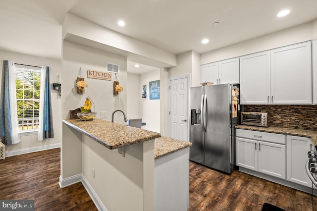 kitchen with dark wood-type flooring, a kitchen breakfast bar, light stone counters, white cabinets, and appliances with stainless steel finishes