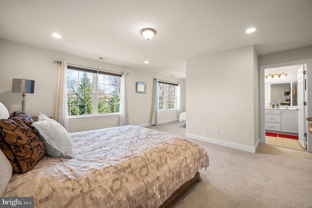 bedroom with light colored carpet and ensuite bath