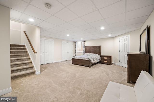 carpeted bedroom featuring two closets and a drop ceiling