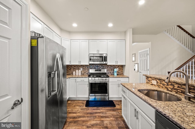 kitchen featuring dark wood-type flooring, sink, light stone countertops, appliances with stainless steel finishes, and white cabinetry