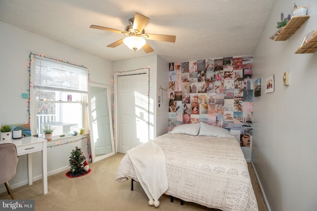 carpeted bedroom with ceiling fan, a textured ceiling, and a closet