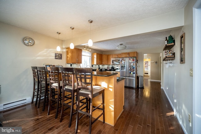 kitchen featuring a breakfast bar, kitchen peninsula, stainless steel appliances, and dark wood-type flooring