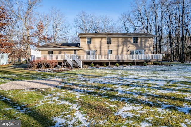 snow covered house featuring a lawn and a wooden deck