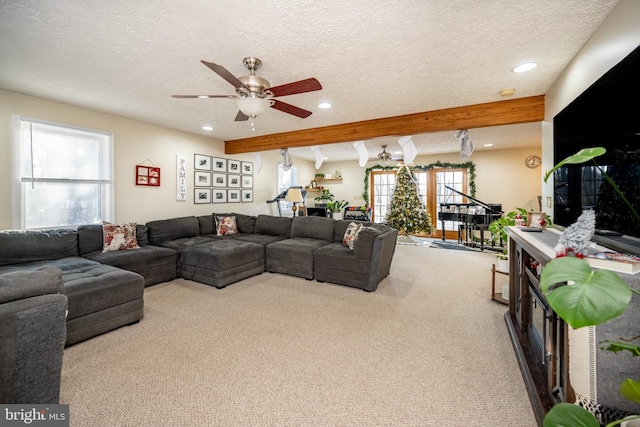 carpeted living room featuring beamed ceiling, a textured ceiling, and ceiling fan