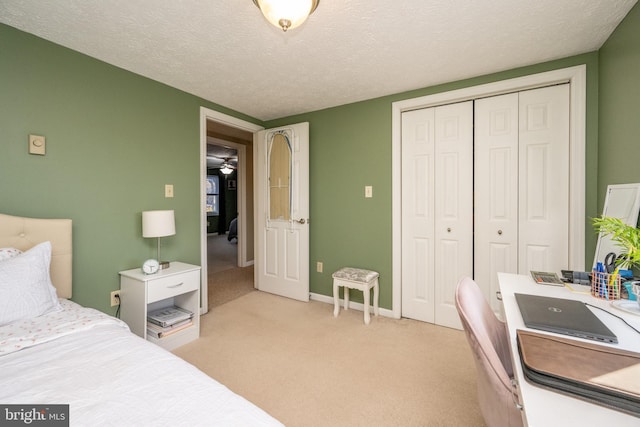 bedroom with a closet, light colored carpet, and a textured ceiling