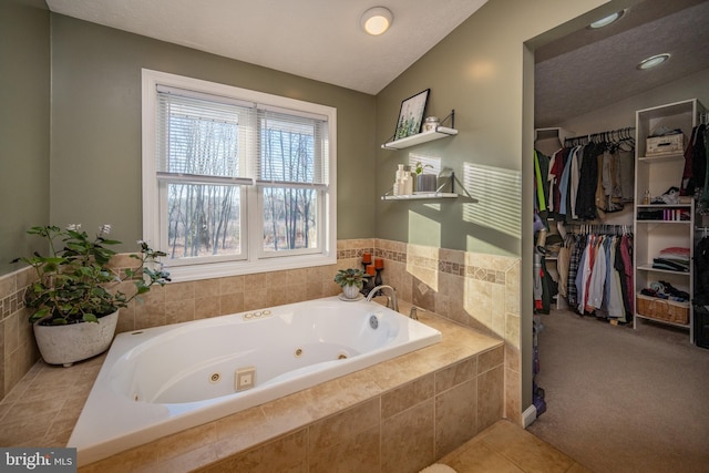 bathroom featuring tile patterned floors, lofted ceiling, a textured ceiling, and tiled tub