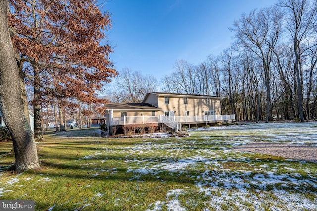 snow covered back of property with a lawn and a wooden deck