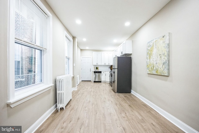 hallway with radiator heating unit and light wood-type flooring