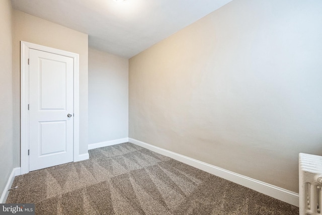 empty room with radiator heating unit and carpet