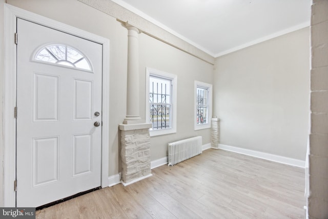 entryway featuring radiator, plenty of natural light, ornate columns, and light hardwood / wood-style flooring