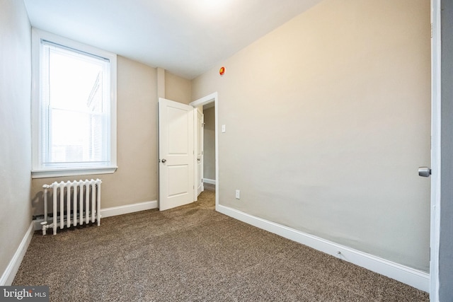 unfurnished bedroom featuring multiple windows, carpet floors, and radiator