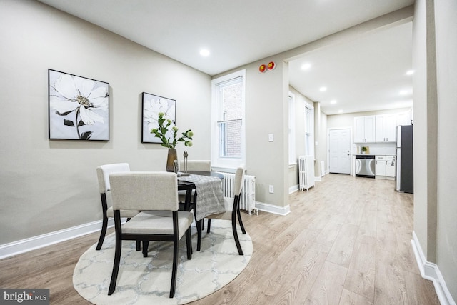 dining space with radiator heating unit and light hardwood / wood-style floors