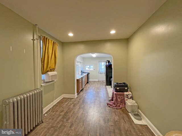 hallway with hardwood / wood-style floors, radiator heating unit, and sink