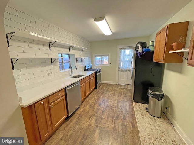 kitchen featuring backsplash, sink, appliances with stainless steel finishes, dark hardwood / wood-style flooring, and light stone counters