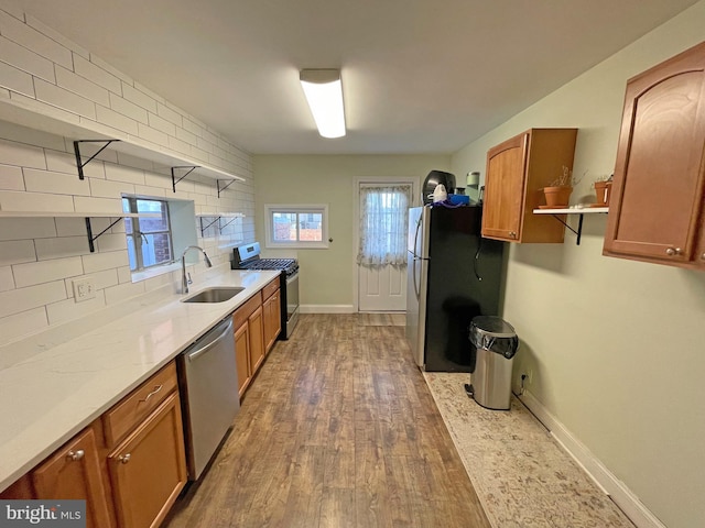 kitchen featuring dark wood-type flooring, sink, decorative backsplash, light stone countertops, and stainless steel appliances