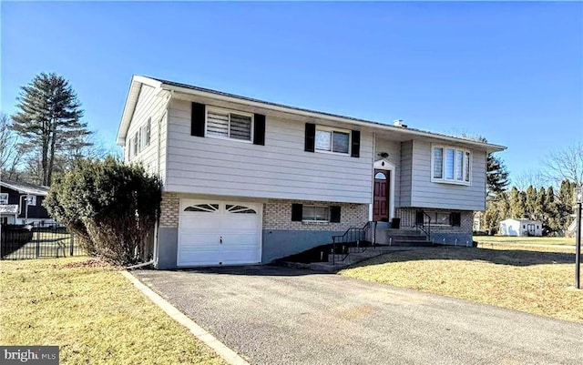 raised ranch featuring a garage and a front lawn