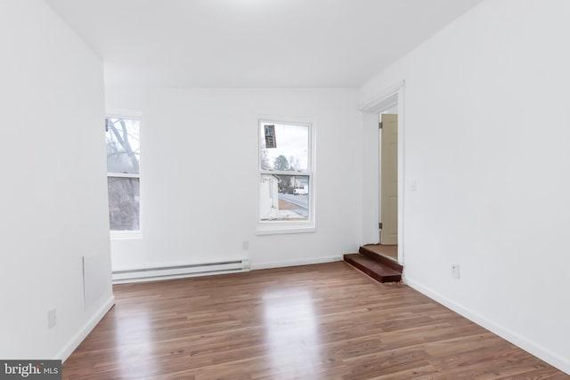 spare room featuring hardwood / wood-style floors, a wealth of natural light, and a baseboard heating unit