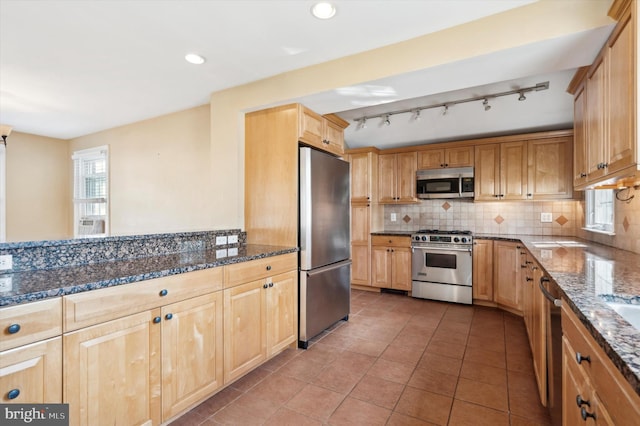 kitchen featuring dark stone countertops, backsplash, tile patterned floors, and appliances with stainless steel finishes