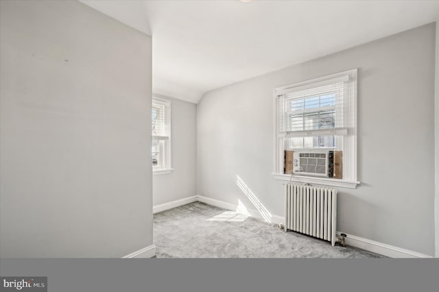 carpeted spare room featuring vaulted ceiling, radiator, a wealth of natural light, and cooling unit