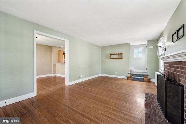 unfurnished living room featuring dark wood-type flooring and a fireplace