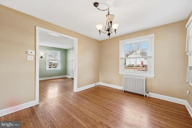 unfurnished dining area with radiator, a notable chandelier, and hardwood / wood-style floors