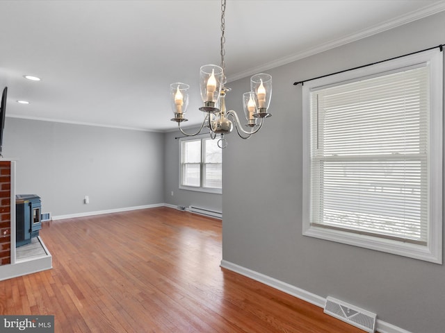 interior space featuring baseboard heating, crown molding, wood-type flooring, a notable chandelier, and a wood stove