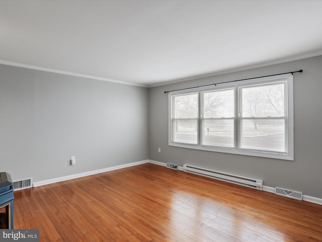 spare room featuring light hardwood / wood-style flooring, baseboard heating, and ornamental molding