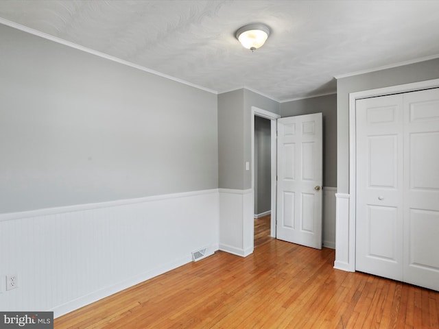 unfurnished bedroom featuring light hardwood / wood-style floors, a closet, and ornamental molding