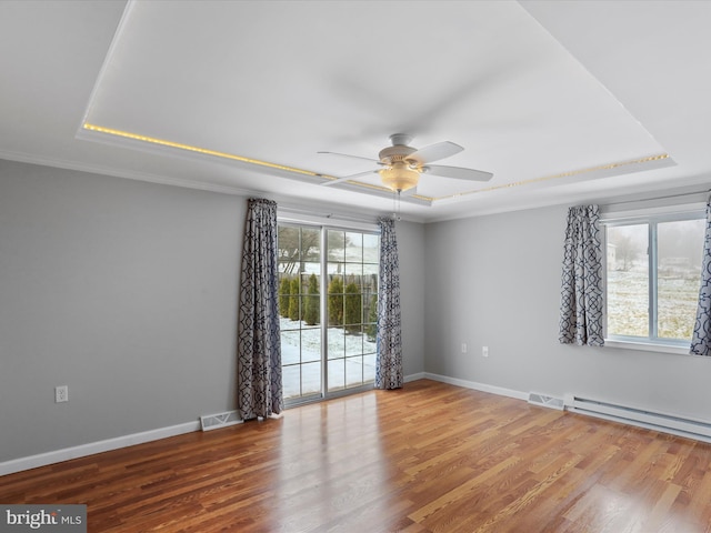 spare room with hardwood / wood-style flooring, a raised ceiling, and a wealth of natural light